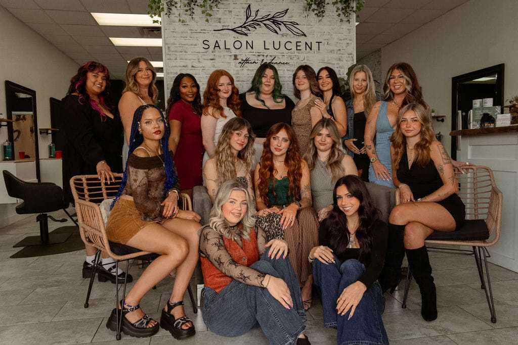 Group of women in a salon posing for a team photo with the "Salon Lucent" sign in the background.